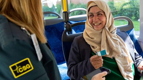 Glad resenär möter biljettkontrollantens blick efter godkänd biljettkontroll på buss.
